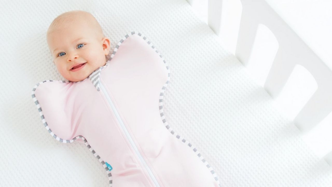 Uśmiechnięte dziecko w różówym kombinezonie piżamie do spania